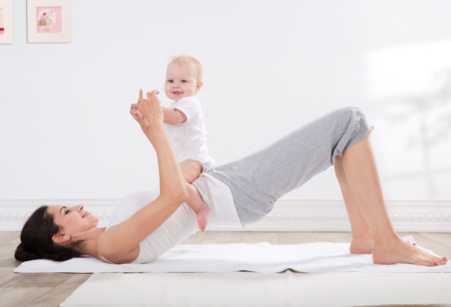 young mother does physical fitness exercises together with her baby